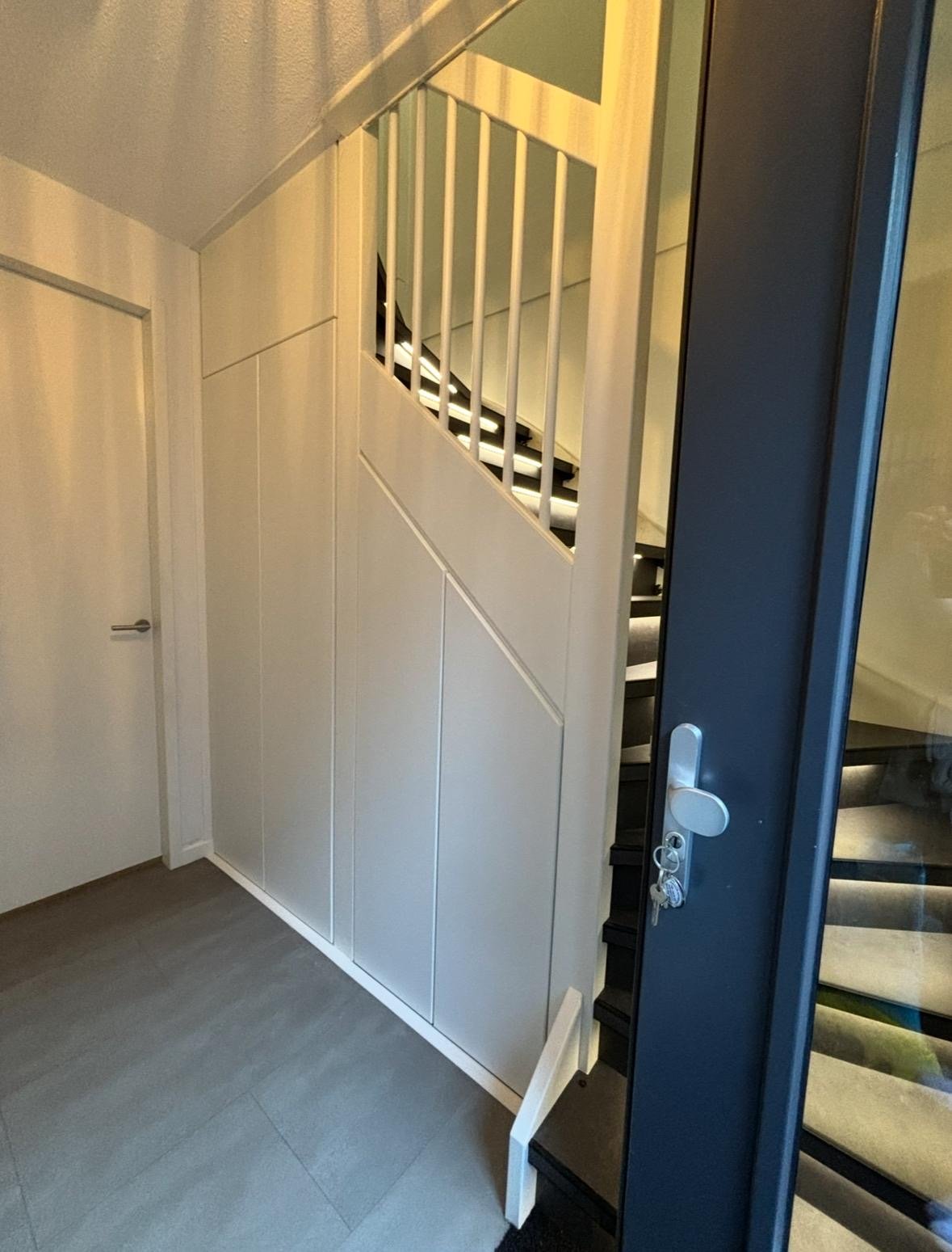 Witte kast onder trap naast voordeur